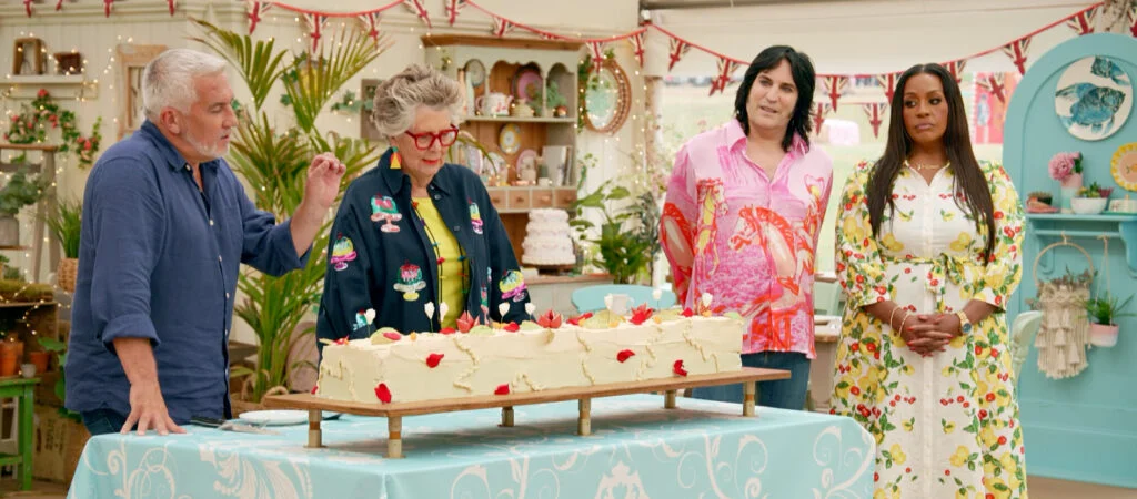 Bake Off presenters look at a large cake