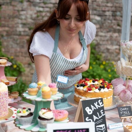 A woman placing cakes on a bake sale table