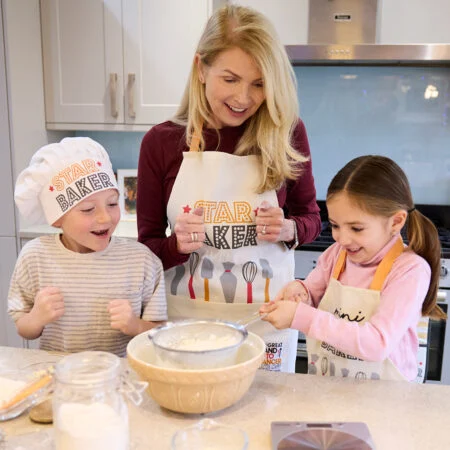 A family bake while wearing Stand Up To Cancer chef's hats and aprons