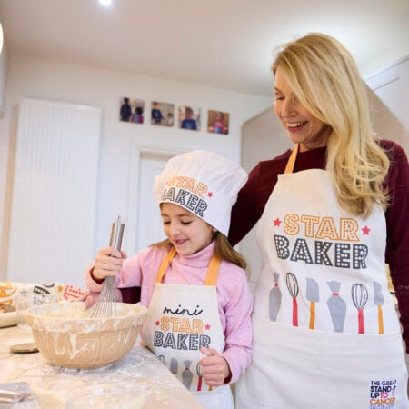 A woman and a girl bake, while wearing Sar Baker chef's hat and aprons